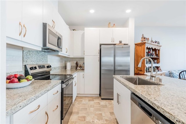 kitchen with white cabinetry, sink, stainless steel appliances, and light stone countertops