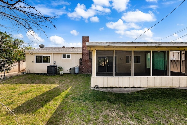 back of property with a yard, a sunroom, and central air condition unit