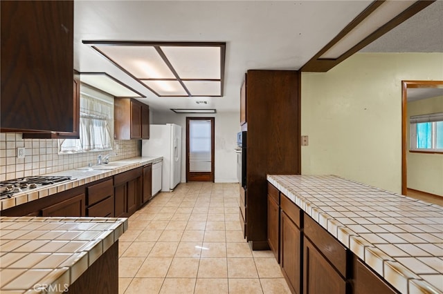 kitchen featuring appliances with stainless steel finishes, tile countertops, sink, backsplash, and light tile patterned floors