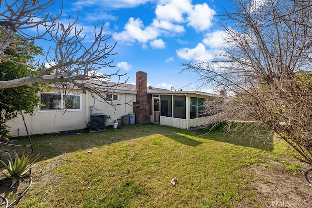 back of property with central AC unit, a lawn, and a sunroom