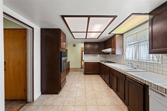 kitchen with tasteful backsplash, sink, tile counters, stainless steel appliances, and dark brown cabinets