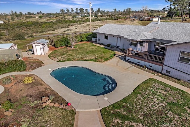 view of pool with a lawn and a storage unit