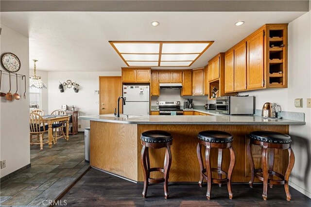 kitchen featuring sink, a breakfast bar area, appliances with stainless steel finishes, hanging light fixtures, and kitchen peninsula