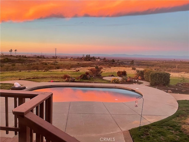 pool at dusk with a patio area