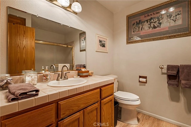 bathroom featuring vanity, hardwood / wood-style floors, toilet, and walk in shower