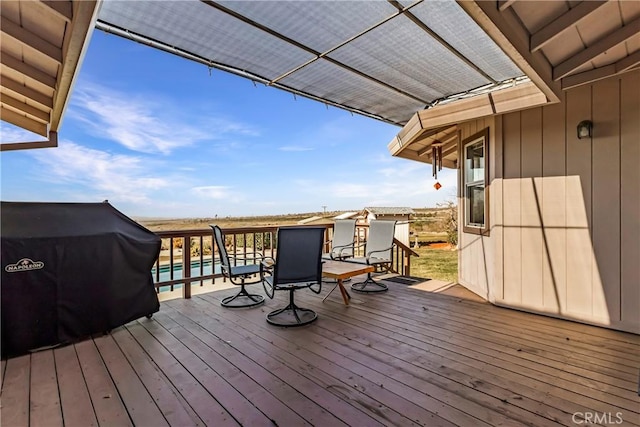 deck with a pool and area for grilling