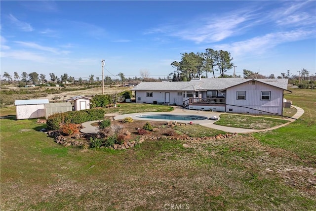 back of property featuring a swimming pool side deck, a storage shed, and a yard