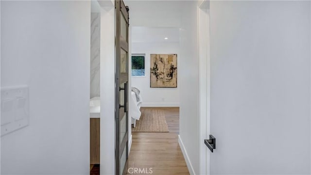 corridor featuring a barn door and light hardwood / wood-style floors