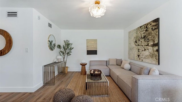 living area featuring visible vents, baseboards, and wood finished floors