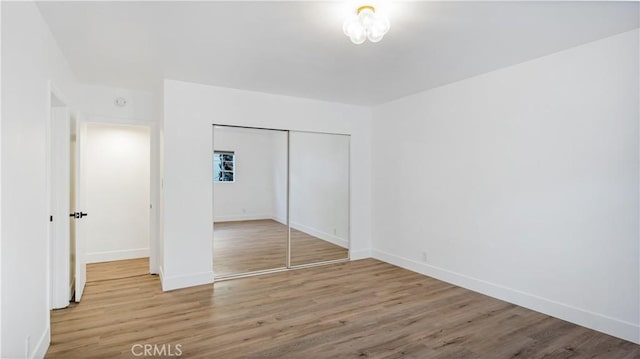 unfurnished bedroom with a closet, baseboards, and wood finished floors