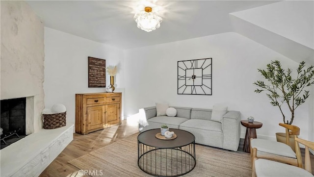 living room with a fireplace with raised hearth and wood finished floors