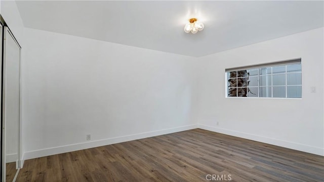 spare room with baseboards and wood finished floors