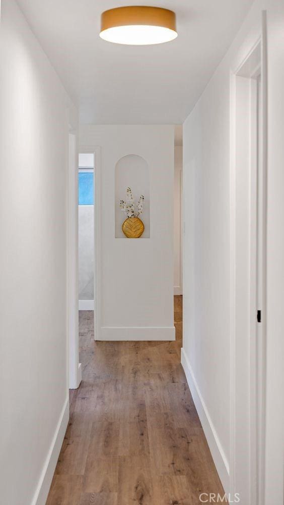 hallway featuring baseboards and wood finished floors