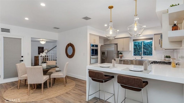 kitchen with visible vents, light countertops, a peninsula, stainless steel appliances, and a sink