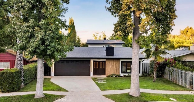 view of front facade featuring fence, an attached garage, a chimney, a front lawn, and concrete driveway