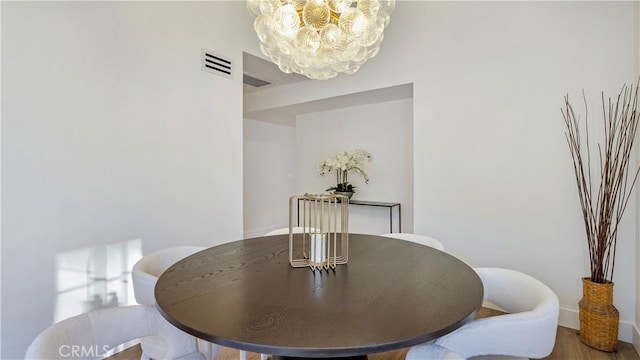 dining room with a notable chandelier, wood finished floors, and visible vents