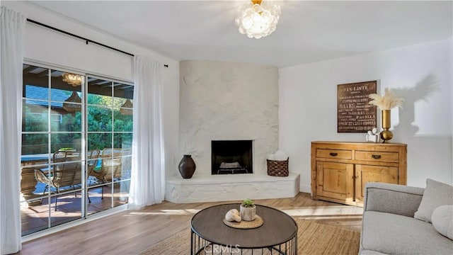 living room featuring a premium fireplace, a chandelier, and light wood-type flooring