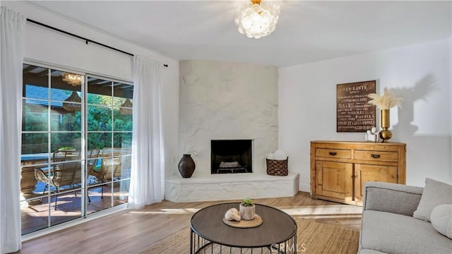 living room featuring an inviting chandelier, light wood-style floors, and a premium fireplace