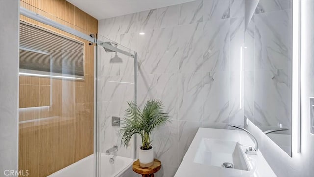 bathroom featuring vanity, tile walls, and shower / bath combination with glass door