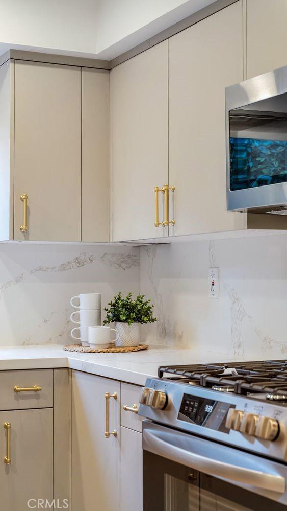 kitchen with tasteful backsplash, light stone countertops, and appliances with stainless steel finishes