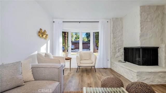 living area with a stone fireplace and wood finished floors