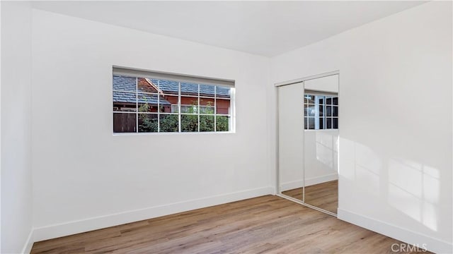 unfurnished bedroom with a closet, baseboards, and wood finished floors