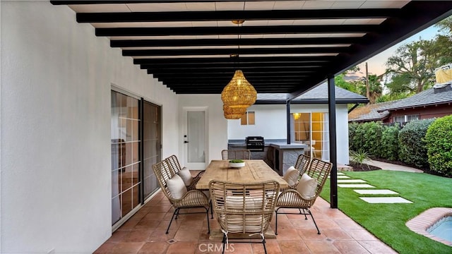 patio terrace at dusk with an outdoor kitchen, a grill, and a lawn