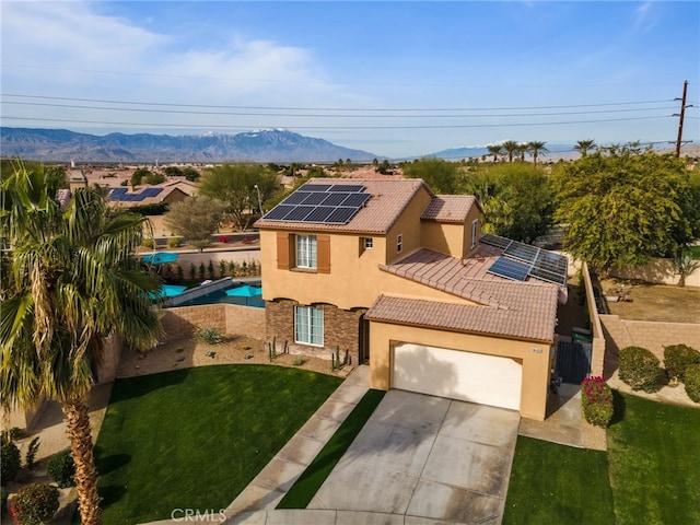 view of front of house with a garage, a mountain view, a front lawn, and solar panels