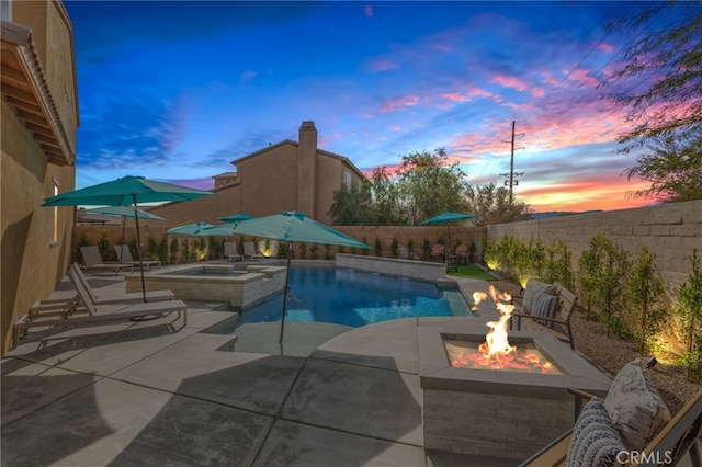 pool at dusk with an in ground hot tub, a patio, and an outdoor fire pit