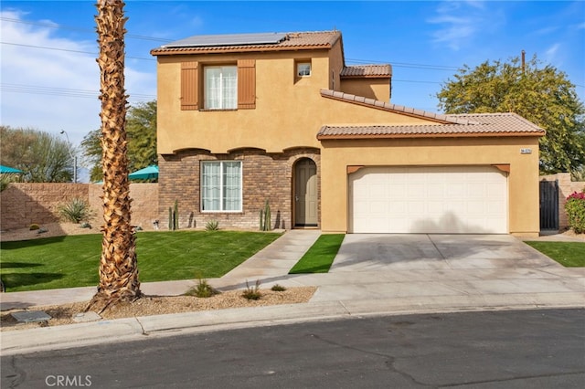 mediterranean / spanish-style home featuring a garage, a front yard, and solar panels