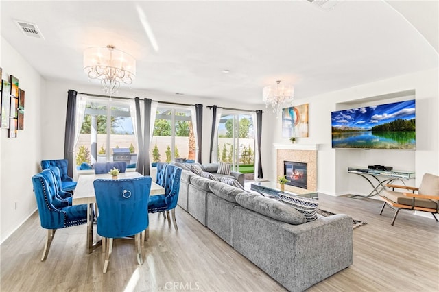 living room featuring plenty of natural light, a notable chandelier, and light hardwood / wood-style flooring