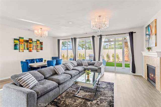 living room with a tile fireplace, a chandelier, and light hardwood / wood-style floors