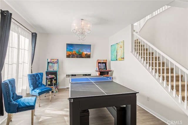 rec room with hardwood / wood-style floors and an inviting chandelier