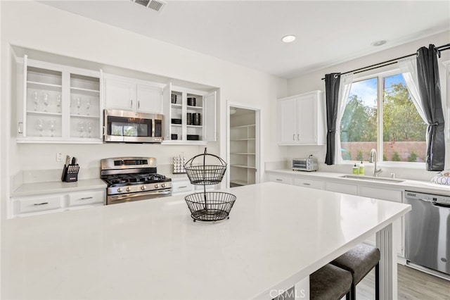 kitchen featuring white cabinetry, appliances with stainless steel finishes, a kitchen breakfast bar, and sink