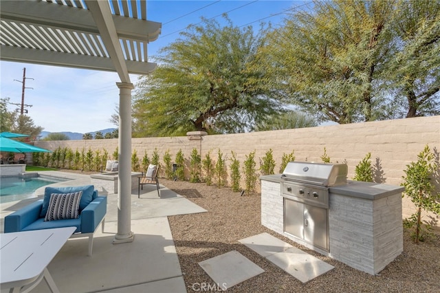 view of patio / terrace with a fenced in pool, grilling area, a pergola, and exterior kitchen