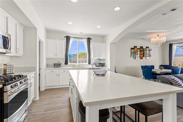 kitchen featuring stainless steel range with gas stovetop, a breakfast bar, sink, and white cabinets