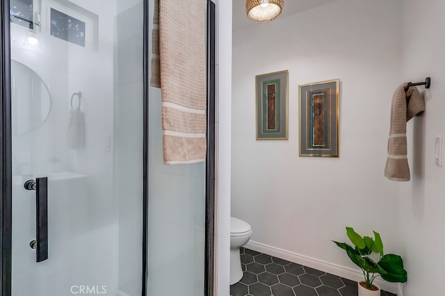 bathroom featuring a shower with shower door and toilet