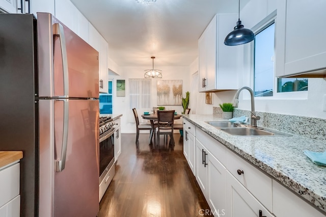 kitchen featuring sink, white cabinetry, hanging light fixtures, dark hardwood / wood-style floors, and stainless steel appliances