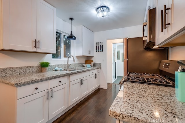 kitchen featuring decorative light fixtures, white cabinetry, sink, light stone counters, and stainless steel range with gas stovetop