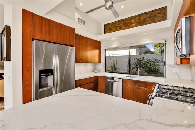 kitchen featuring light stone counters, appliances with stainless steel finishes, kitchen peninsula, and sink