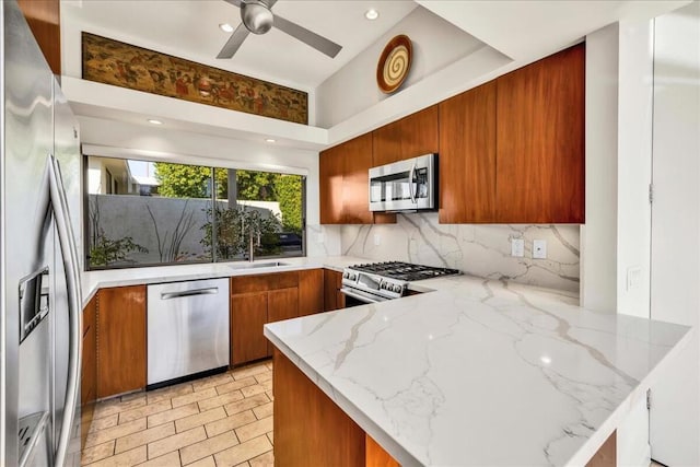 kitchen with appliances with stainless steel finishes, kitchen peninsula, and light stone countertops