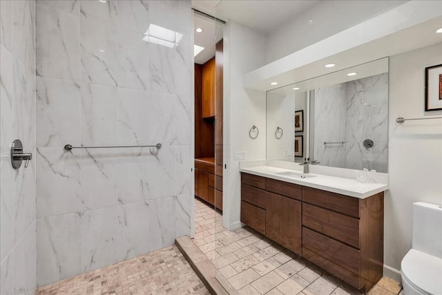 bathroom featuring vanity, tiled shower, and toilet