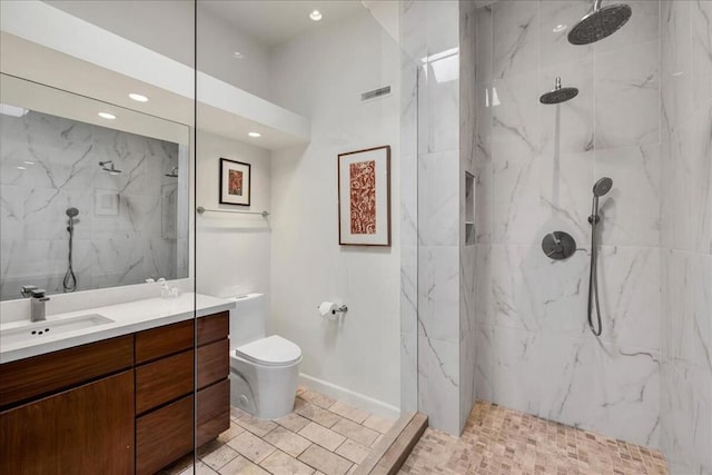 bathroom with tiled shower, vanity, and toilet