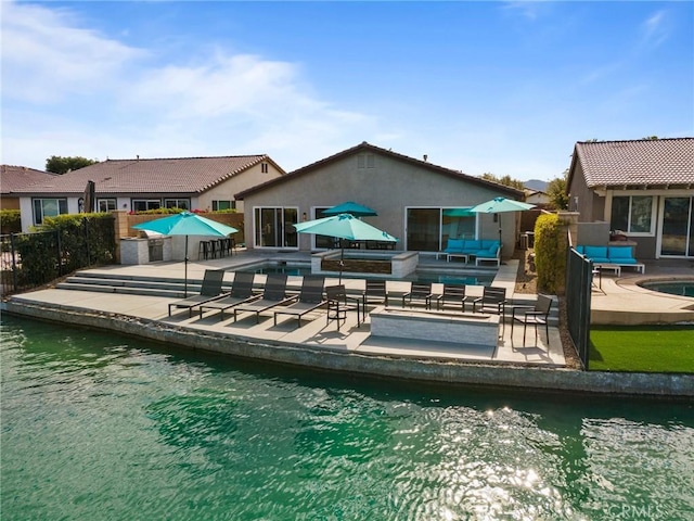 back of house featuring an outdoor living space, a patio, and a water view