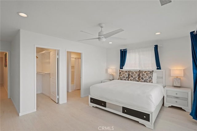 bedroom featuring ceiling fan, a walk in closet, a closet, and light wood-type flooring