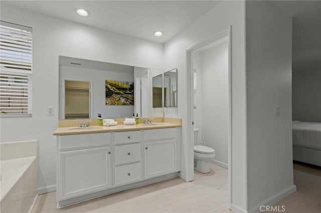 bathroom featuring vanity, hardwood / wood-style floors, a bathtub, and toilet