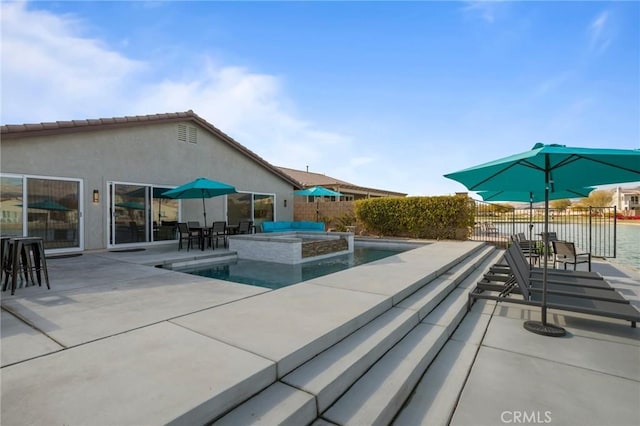 view of pool with an in ground hot tub, a water view, and a patio