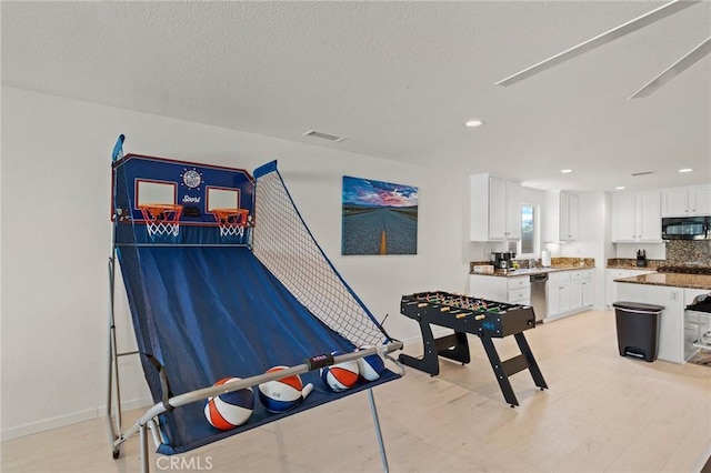 game room featuring a textured ceiling and light hardwood / wood-style floors