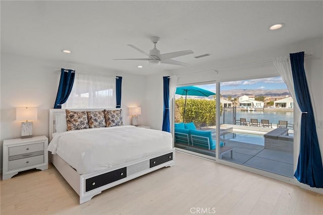 bedroom featuring a water view, ceiling fan, wood-type flooring, and access to outside