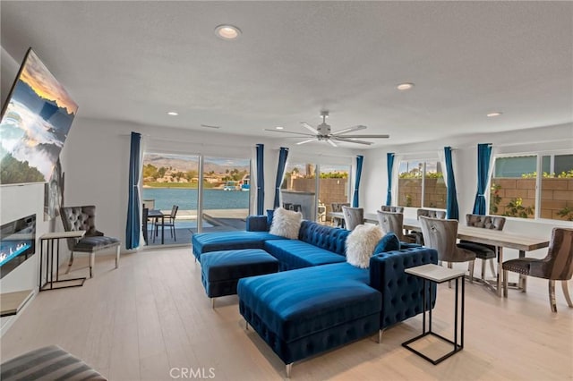 living room featuring plenty of natural light, light hardwood / wood-style floors, and a water view